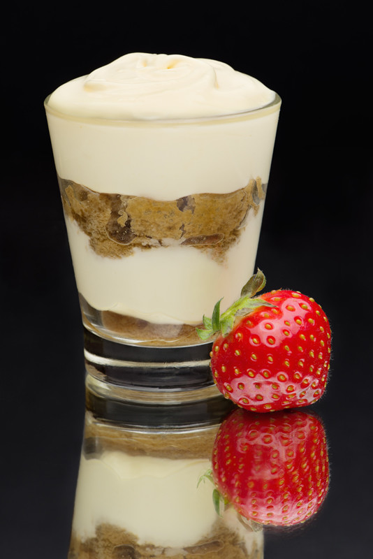 Tiramisu in a glass with strawberry on a mirror