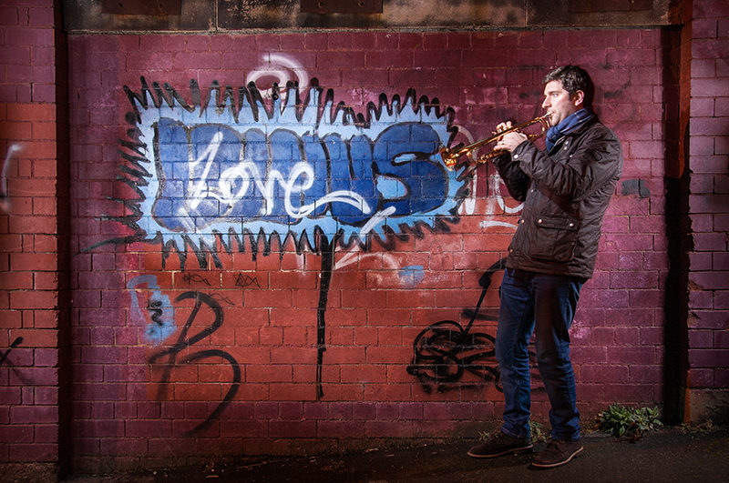 Light painting of musician and education Finlay Hetherington in front of a graffiti wall with his trumpet