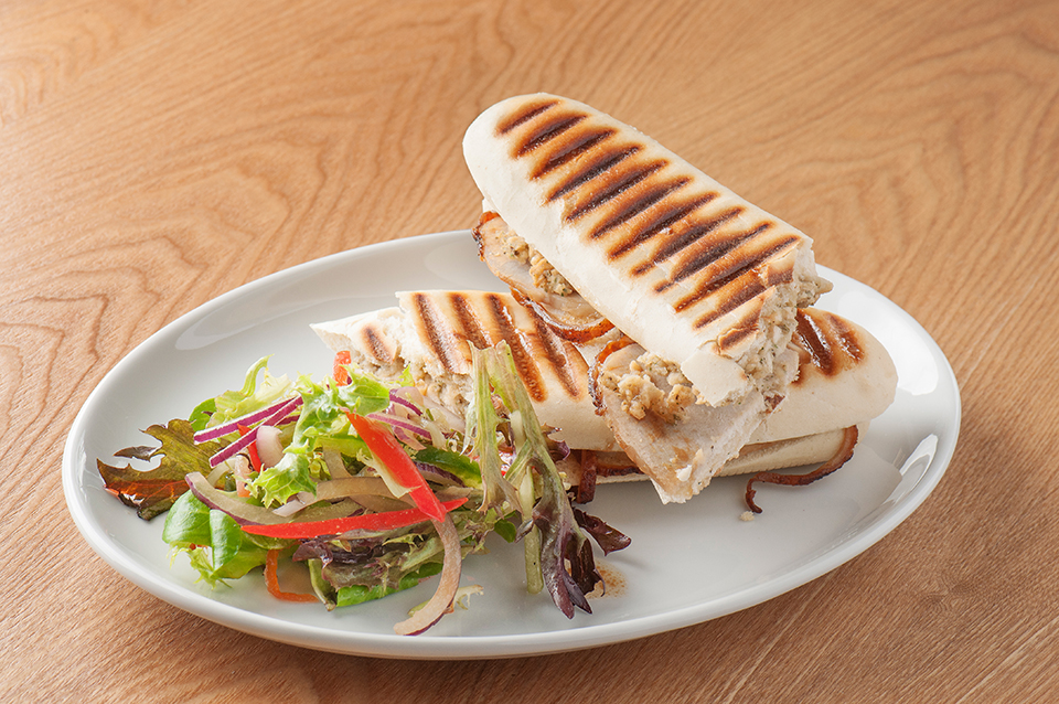 Chicken panini sandwich on a plate with side salad