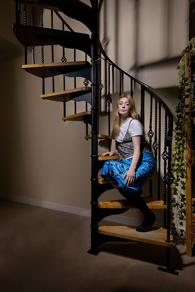Light painting of singer Katie sitting on a staircase and looking at the camera