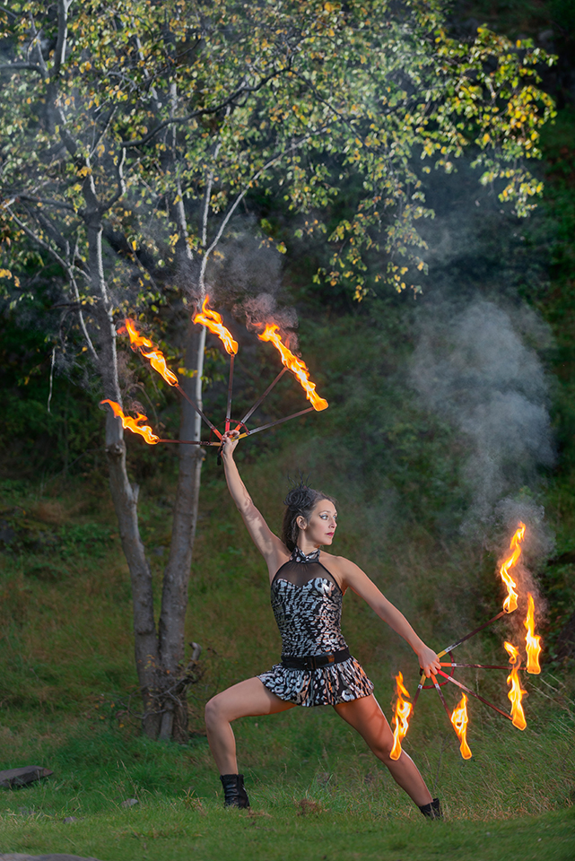 Circus artist Zoja Dravai handling fire under a tree
