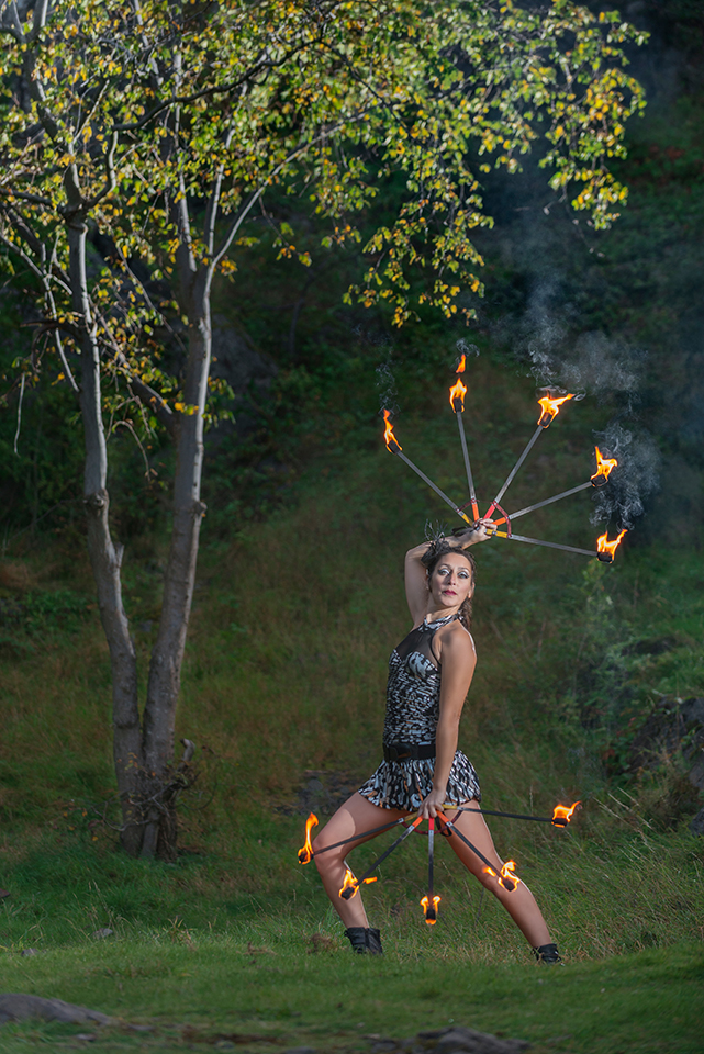 Circus artist Zoja Dravai handling fire under a tree