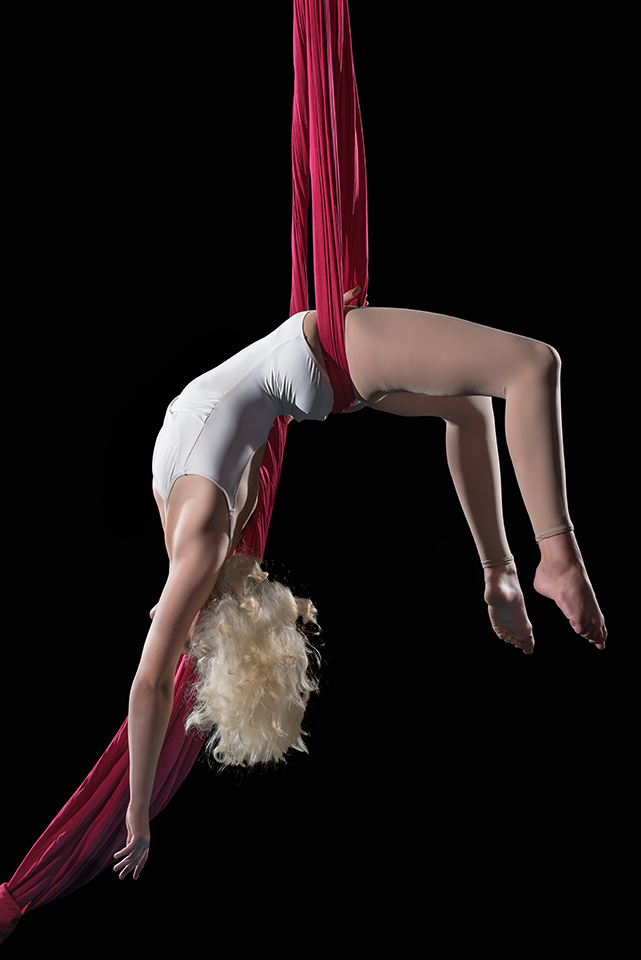 Ella hanging upside down, sitting on the silks