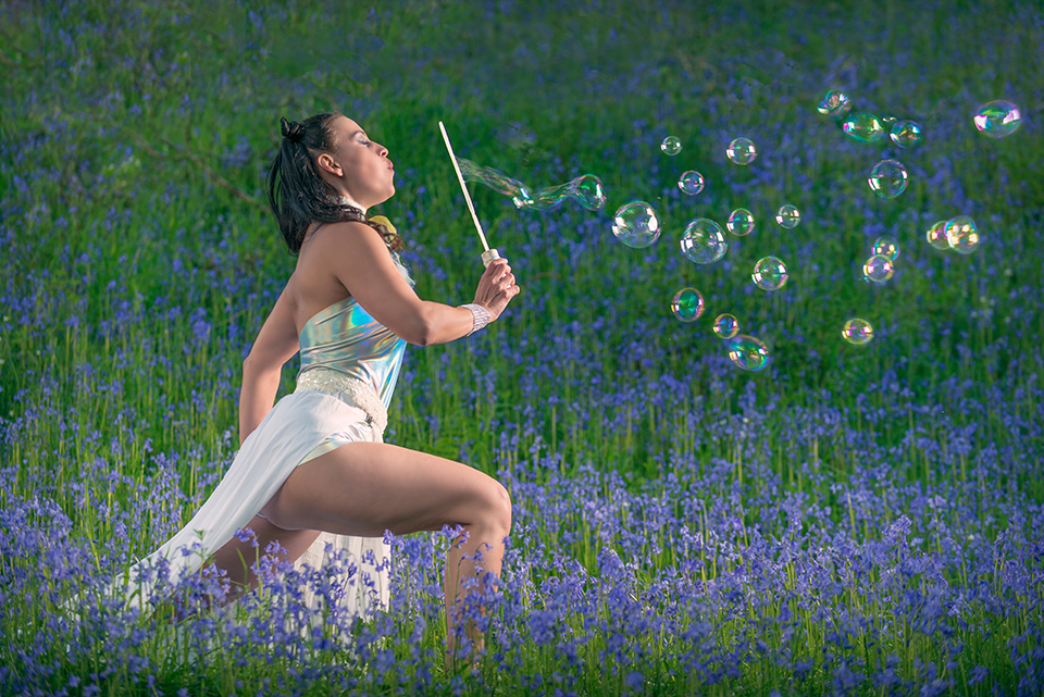 Model blowing soap bubbles in a field of bluebells