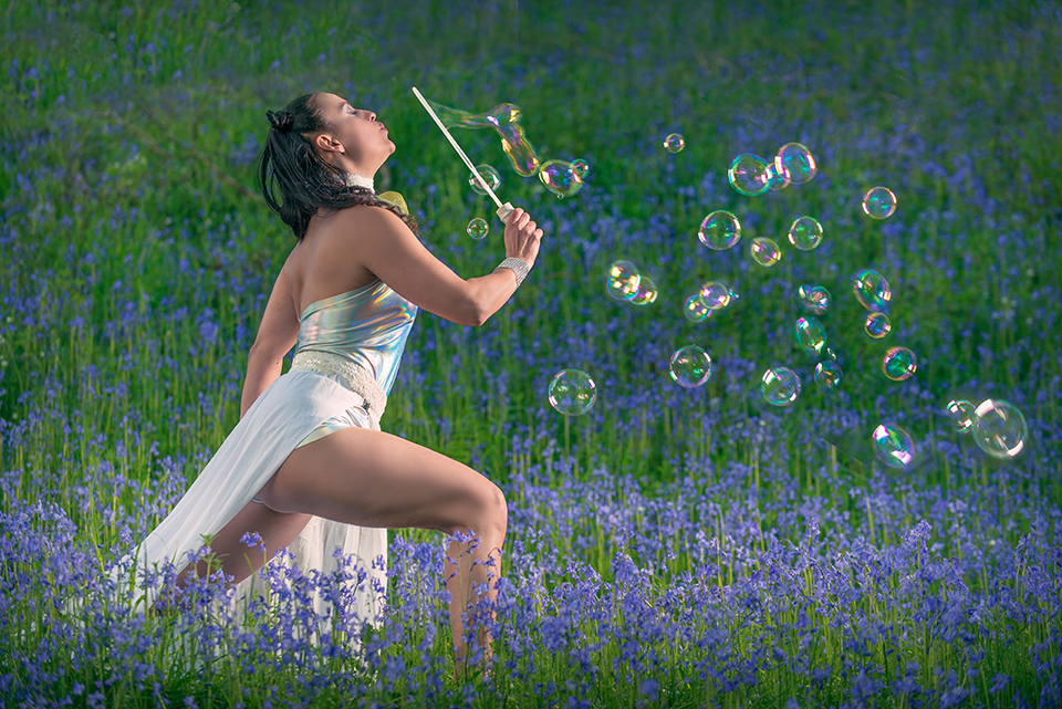 Jusztina blowing soap bubbles in a field of bluebells
