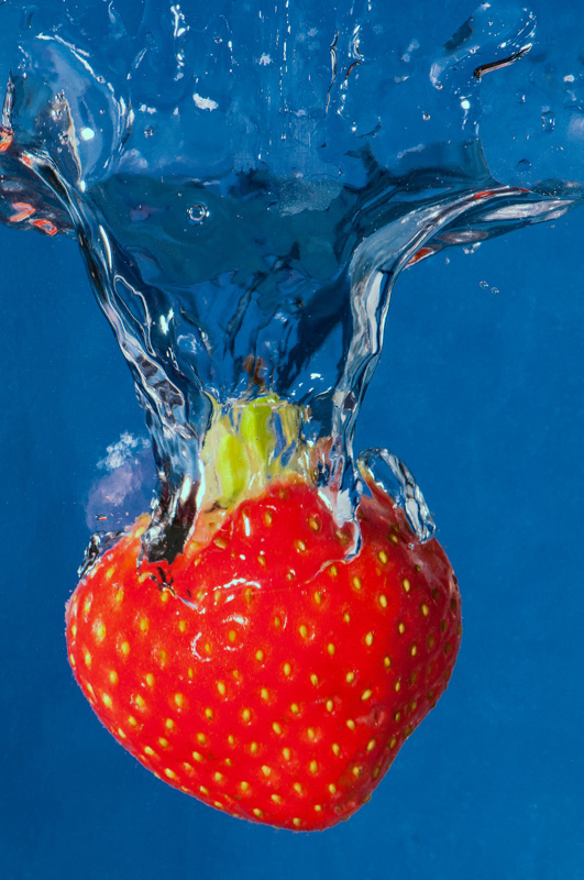 The blue background creates a strong colour contrast with the red strawberry, making it 'pop'
