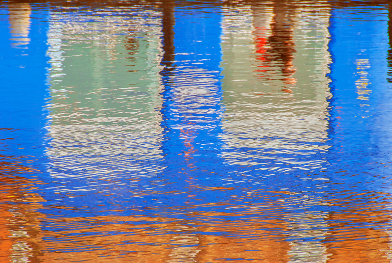 Reflection of pedestrians and colourful building in the Water of Leith river, Edinburgh