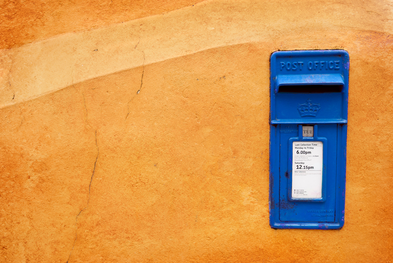 Musselburgh mailbox on an orange wall. The colour of the mailbox was changed from red to blue