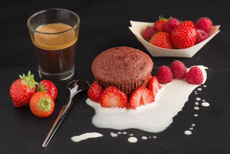 Red velvet cupcake with cream, strawberries and some Italian coffee on a black slate.