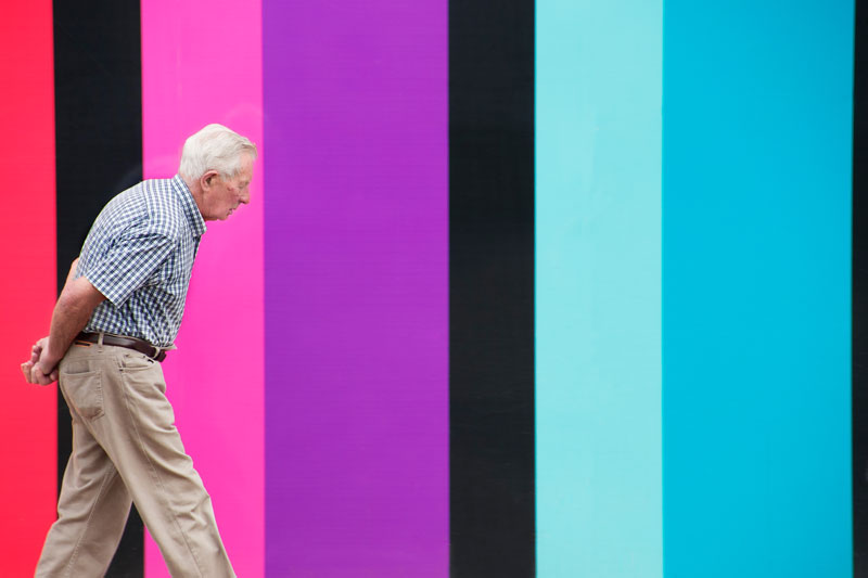 Older gentleman walking in front of a very colourful wall in Edinburgh, Scotland