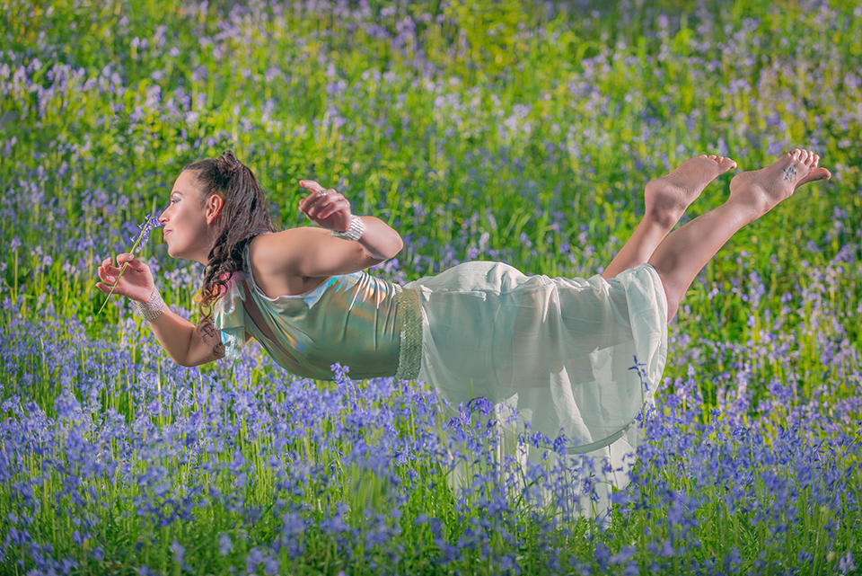 Circus artist Jusztina Hermann levitating in a field of bluebells